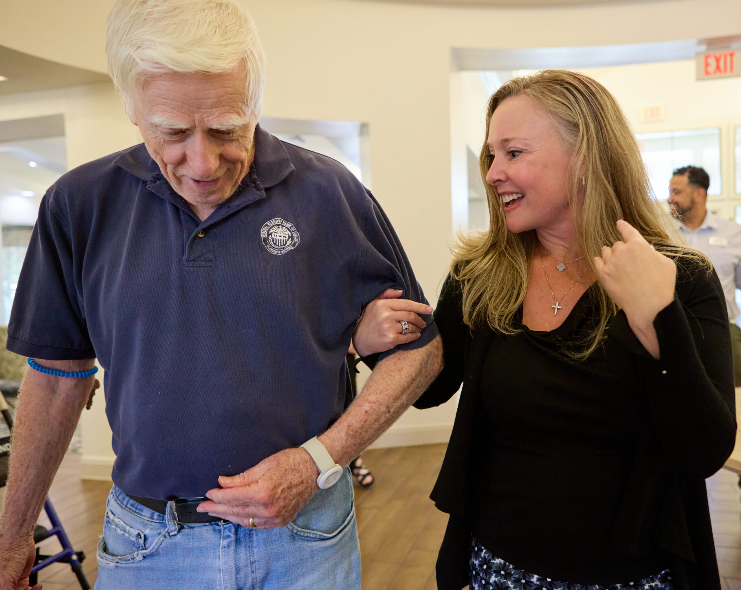 Older man walking with a caregiver at Village on the Park Denton Assisted Living Community in Denton, Texas